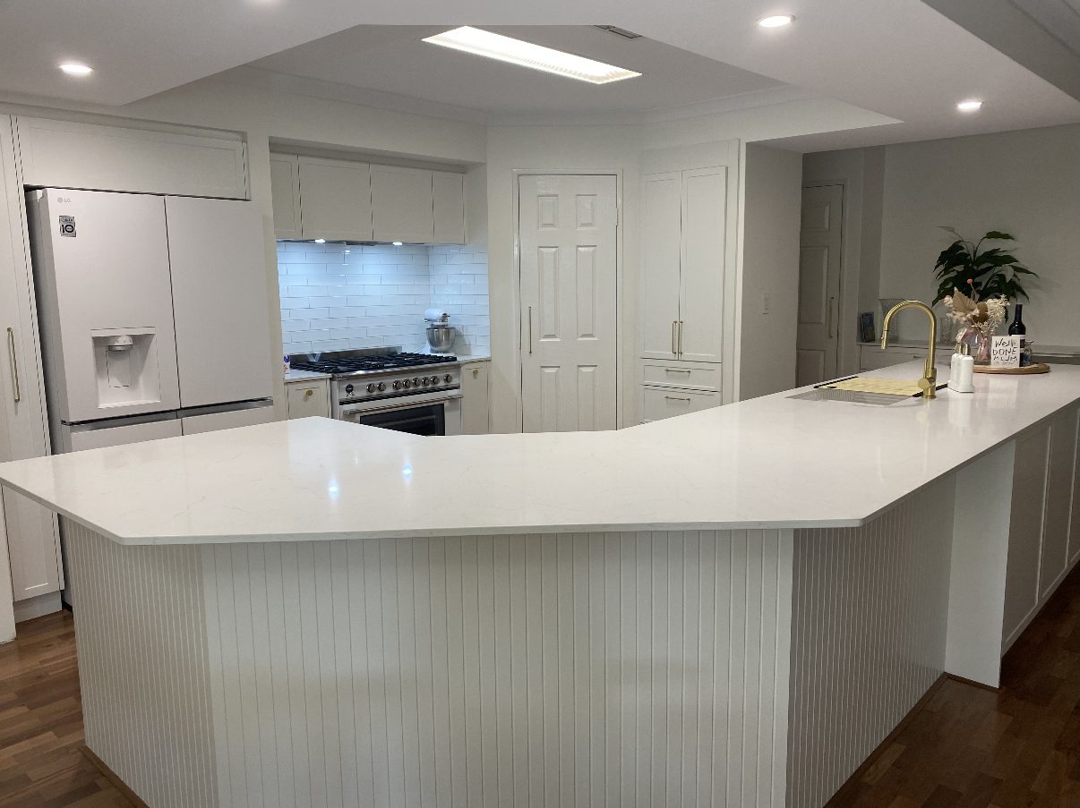 Completed kitchen renovation with stone benchtop, panelled island and brass tapware