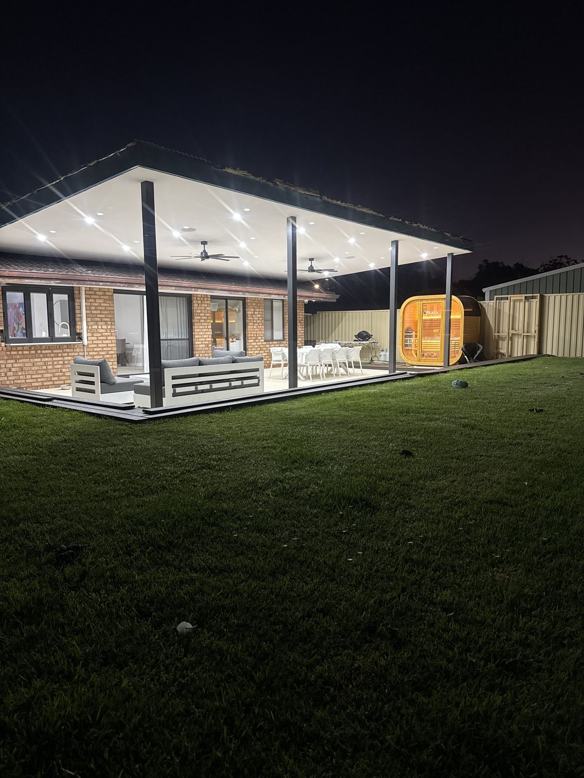 Completed outdoor entertaining area with lit alfresco and sauna at night